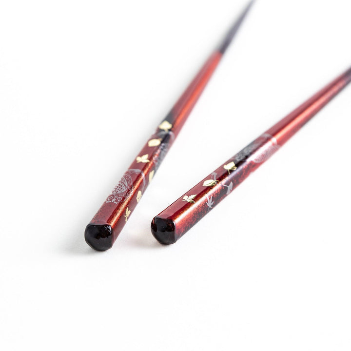 Two pairs of chopsticks in black and red, with golden owl and leaf designs and Japanese text inscriptions.