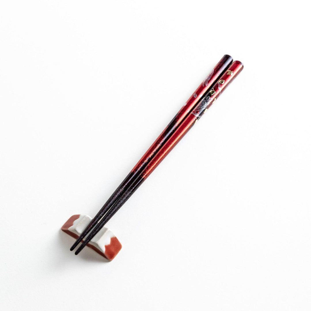 Two pairs of chopsticks in black and red, with golden owl and leaf designs and Japanese text inscriptions.