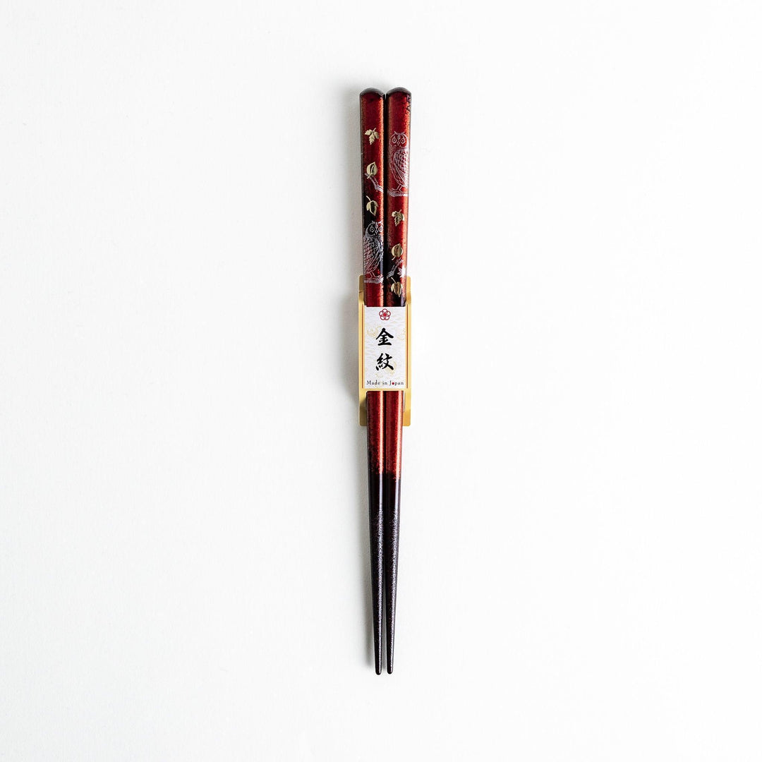 Two pairs of chopsticks in black and red, with golden owl and leaf designs and Japanese text inscriptions.